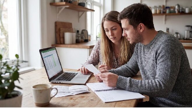 Person reviewing personal budget on a laptop and notebook