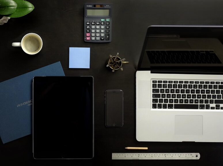 Two budgeting apps compared on a desk with notebook and calculator