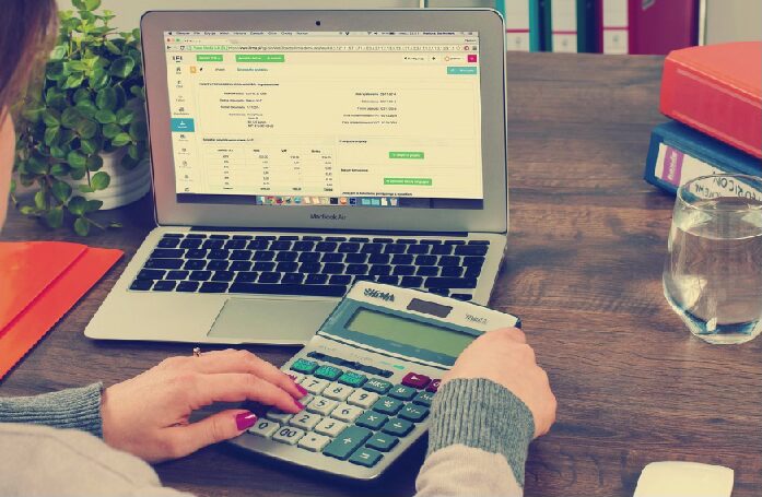 Person planning debt payoff with calculator and notebook